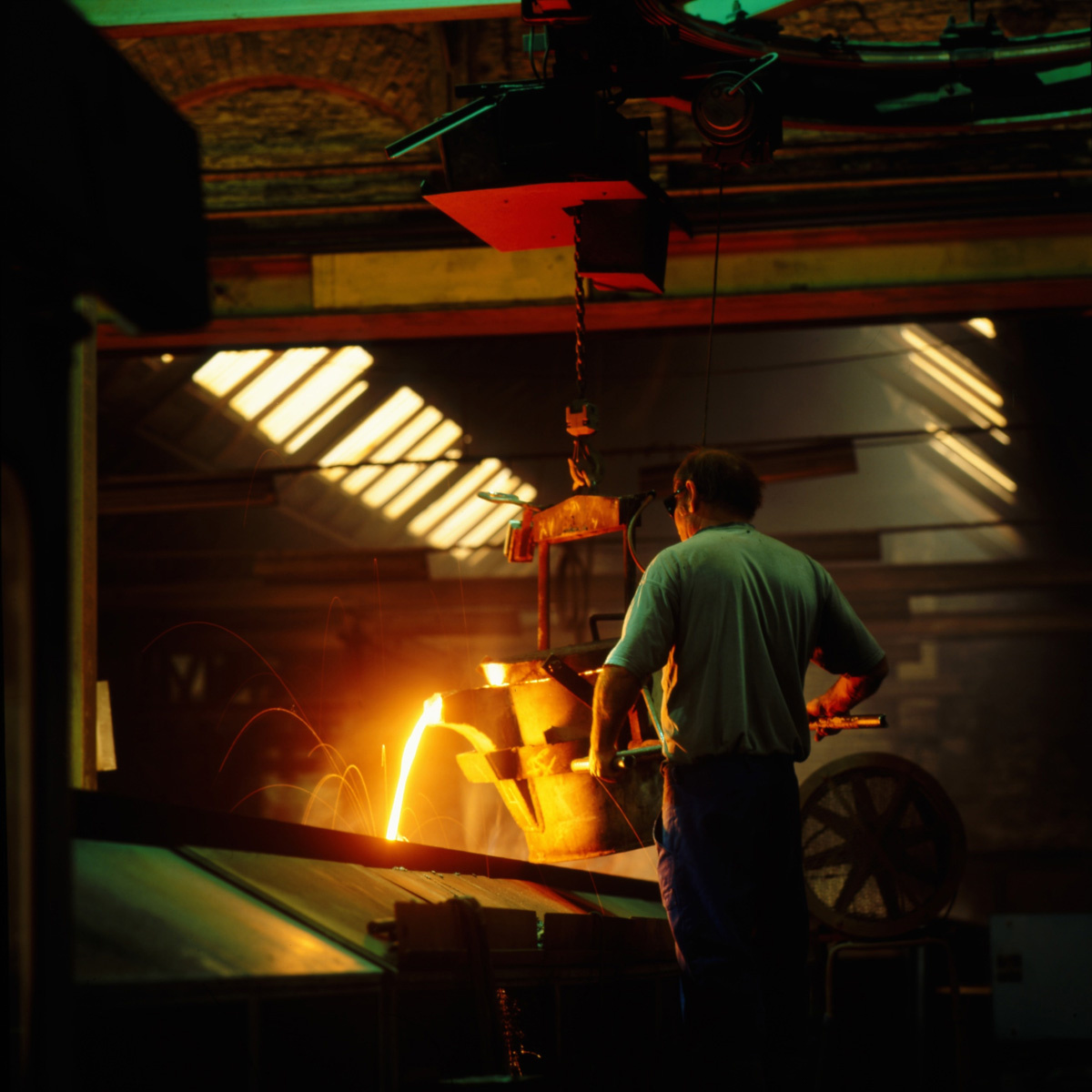 La photographie montre un fondeur au travail dans l’usine Godin SA de Guise.