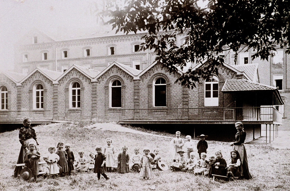 Des enfants posent sur l'herbe, devant la crèche du Familistère.
