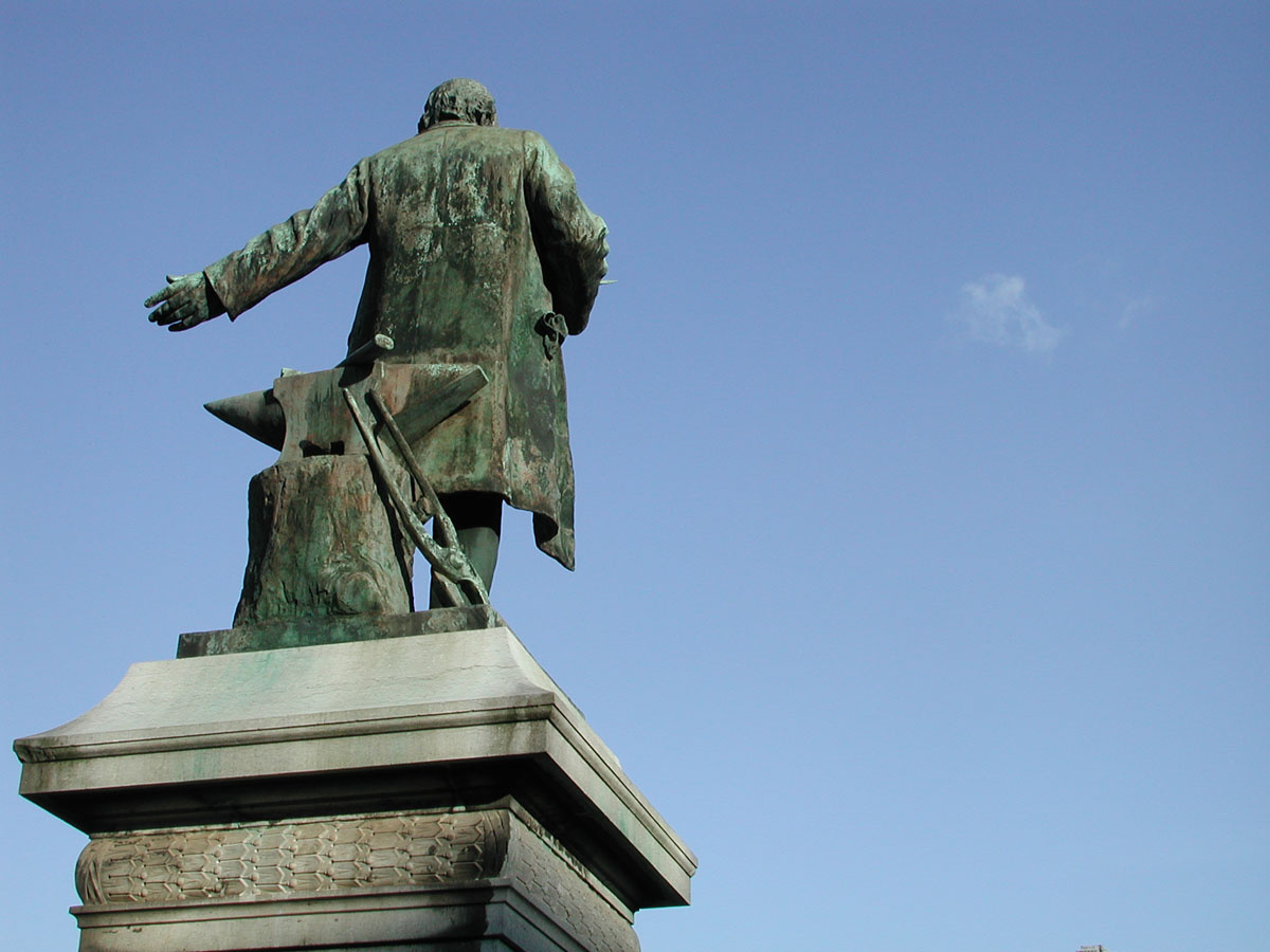 La statue de Godin se détache sur un ciel bleu uniquement taché par un petit nua