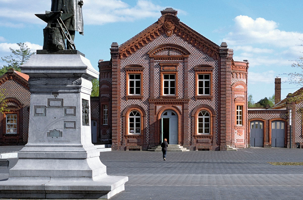 La façade du théâtre du Familistère est vue du piédestal de la statue de Godin.