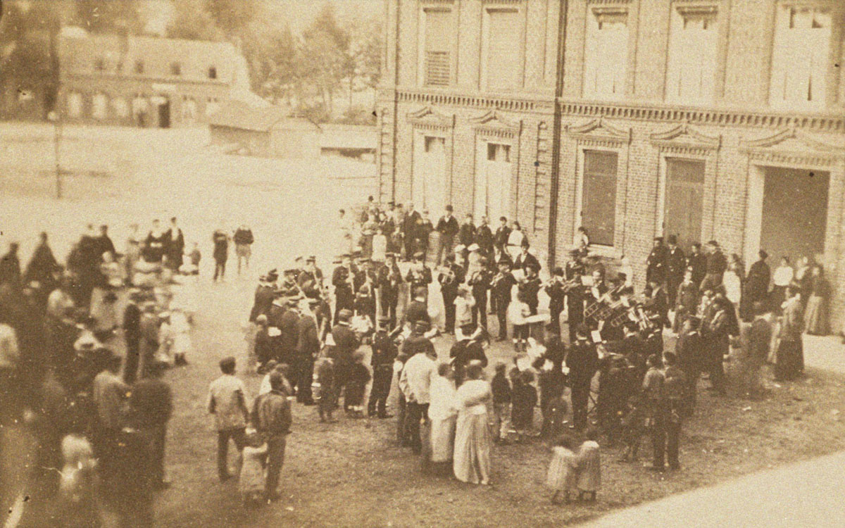 La photographie montre la Société musicale de Guise en 1881 sur la place du Fami