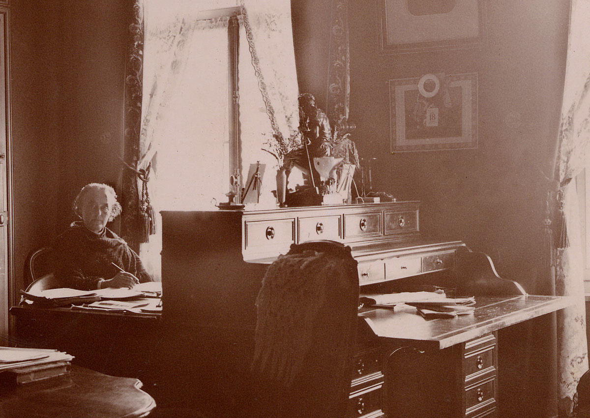 La photographie montre Marie Moret assise devant son bureau.