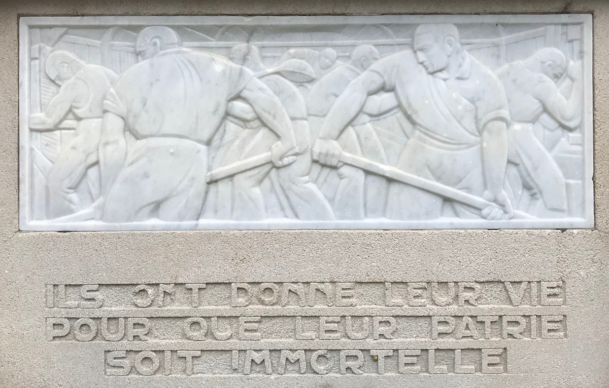 La photographie montre le relief situé à droite sur le monument aux morts du Fam