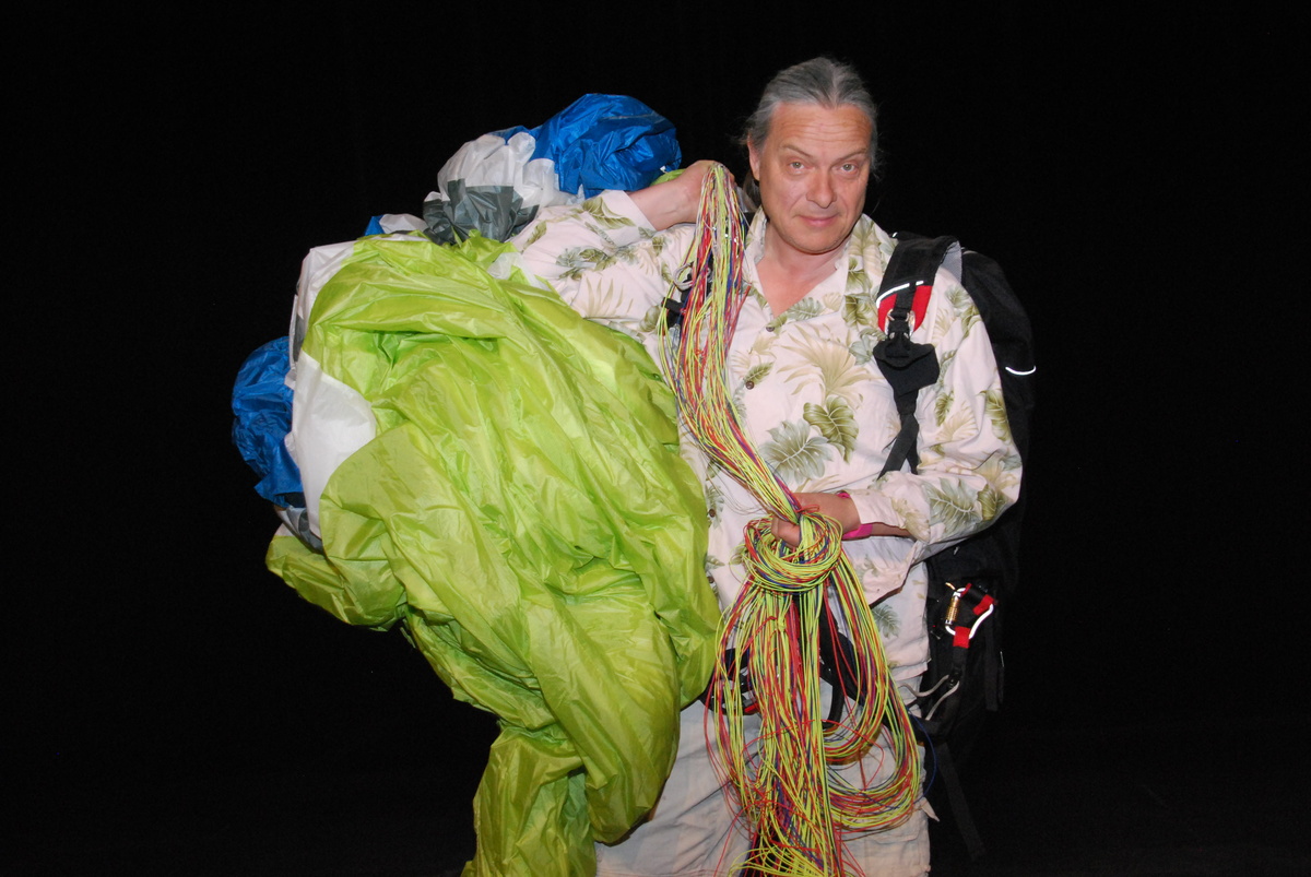 Franck Lepage est équipé de son parapente qu'il tient sur son épaule.