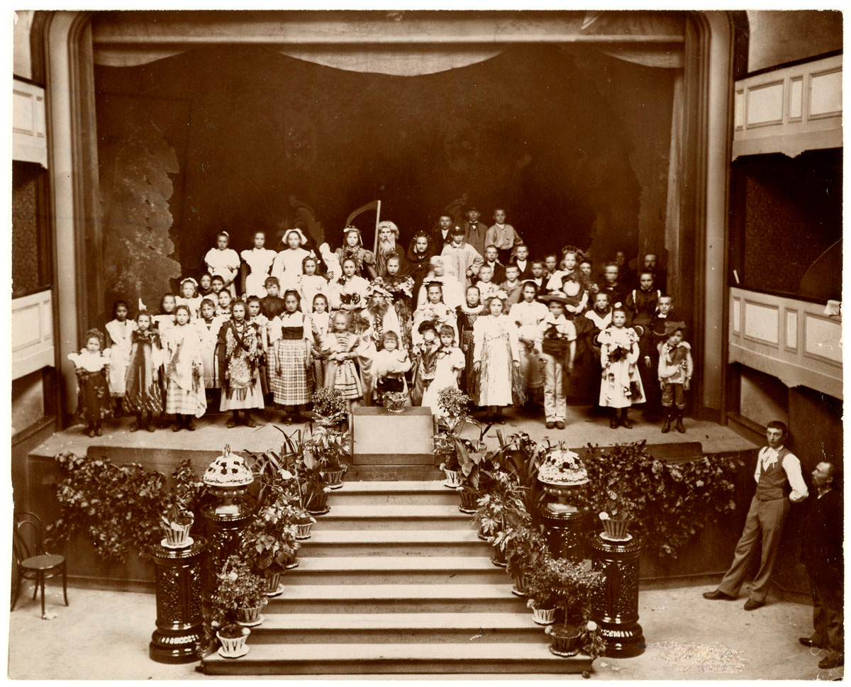 La photographie montre des enfants costumés sur la scène du théâtre du Familistè