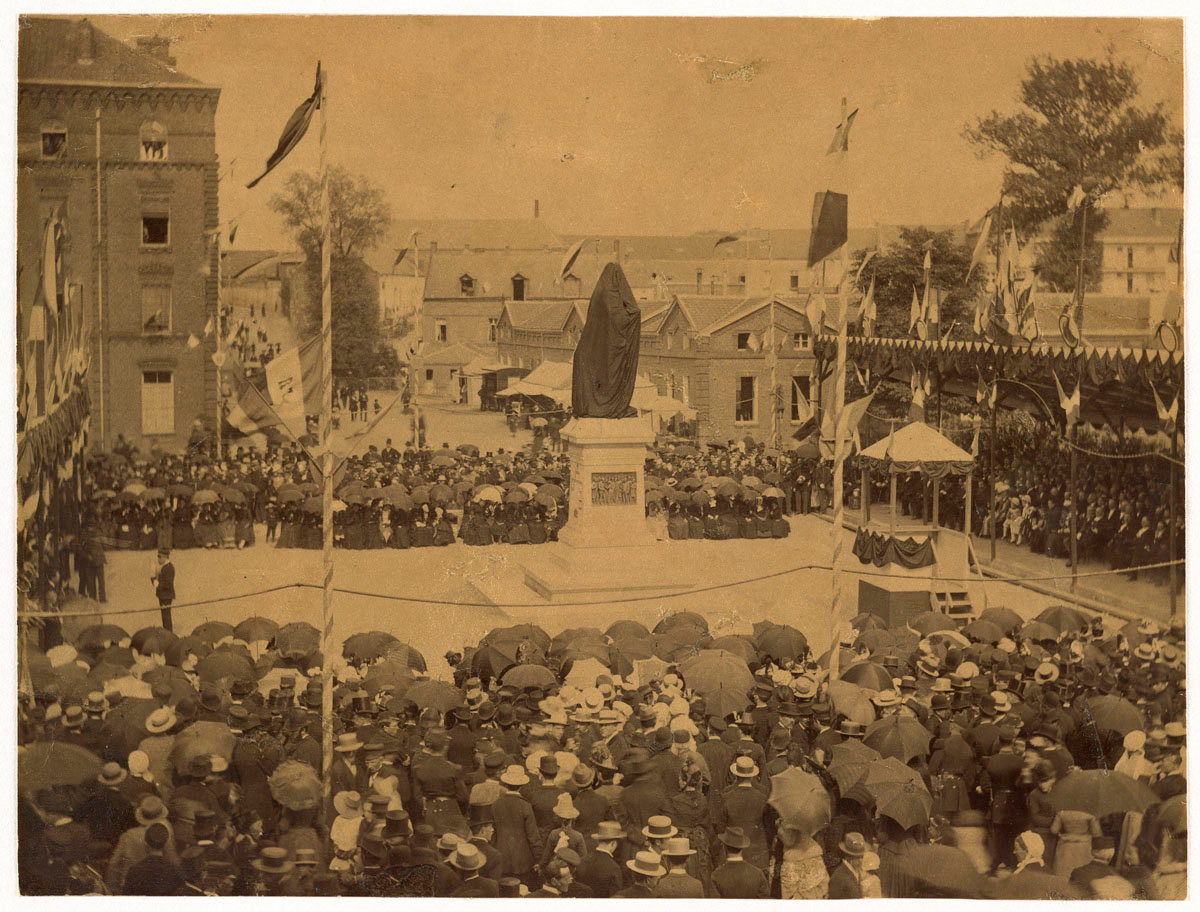 La photographie montre l'inauguration de la statue de Godin, encore voilée