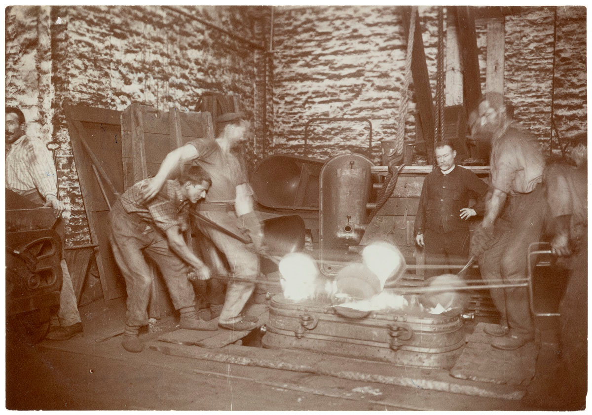 La photographie montre une scène de moulage dans l'usine du Familistère