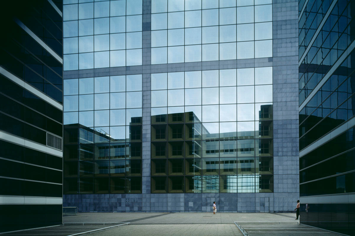 La photographie montre une façade de verre avec deux personnages