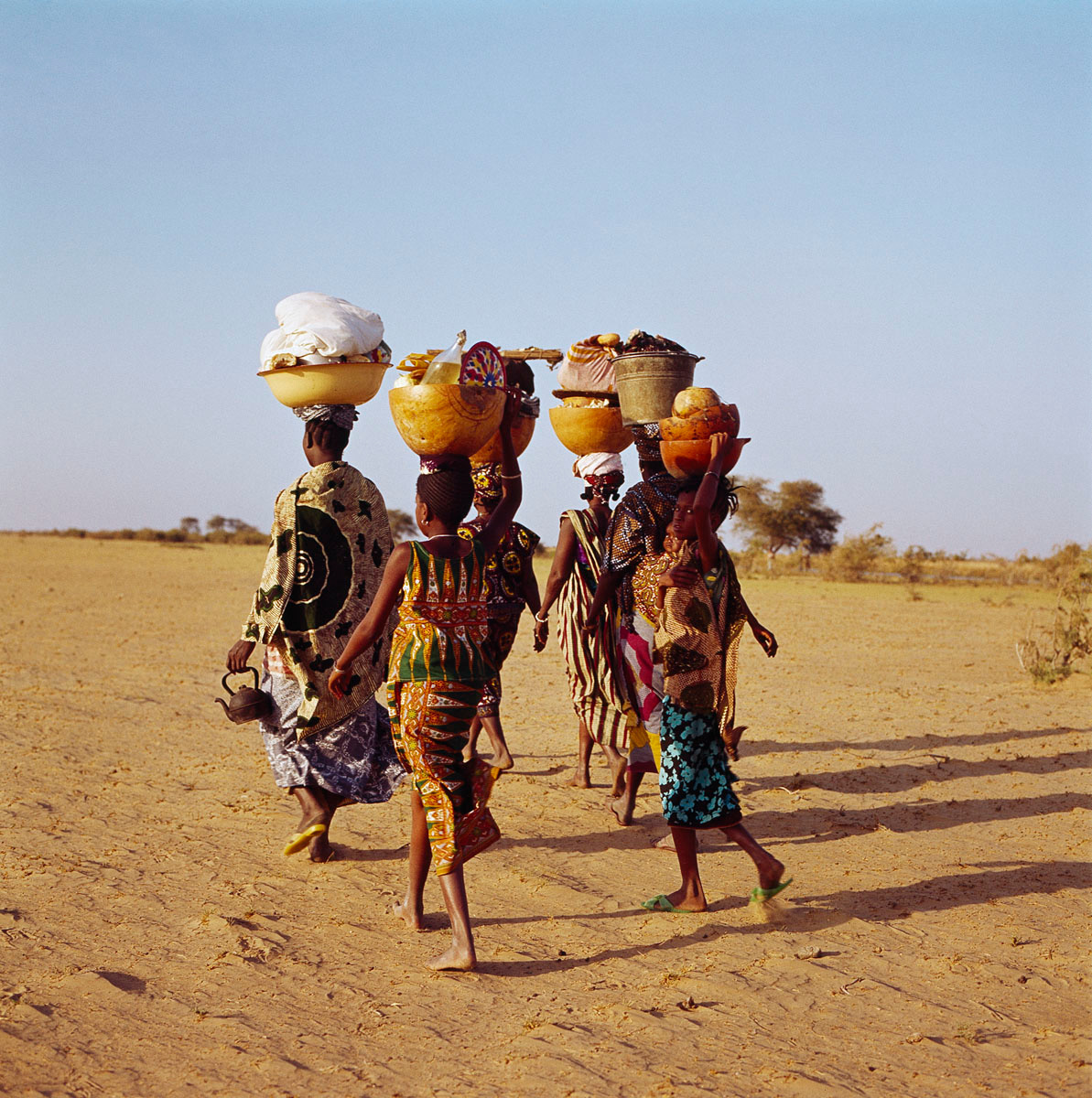 La photographie montre quatre femmes marchant dans le sable.