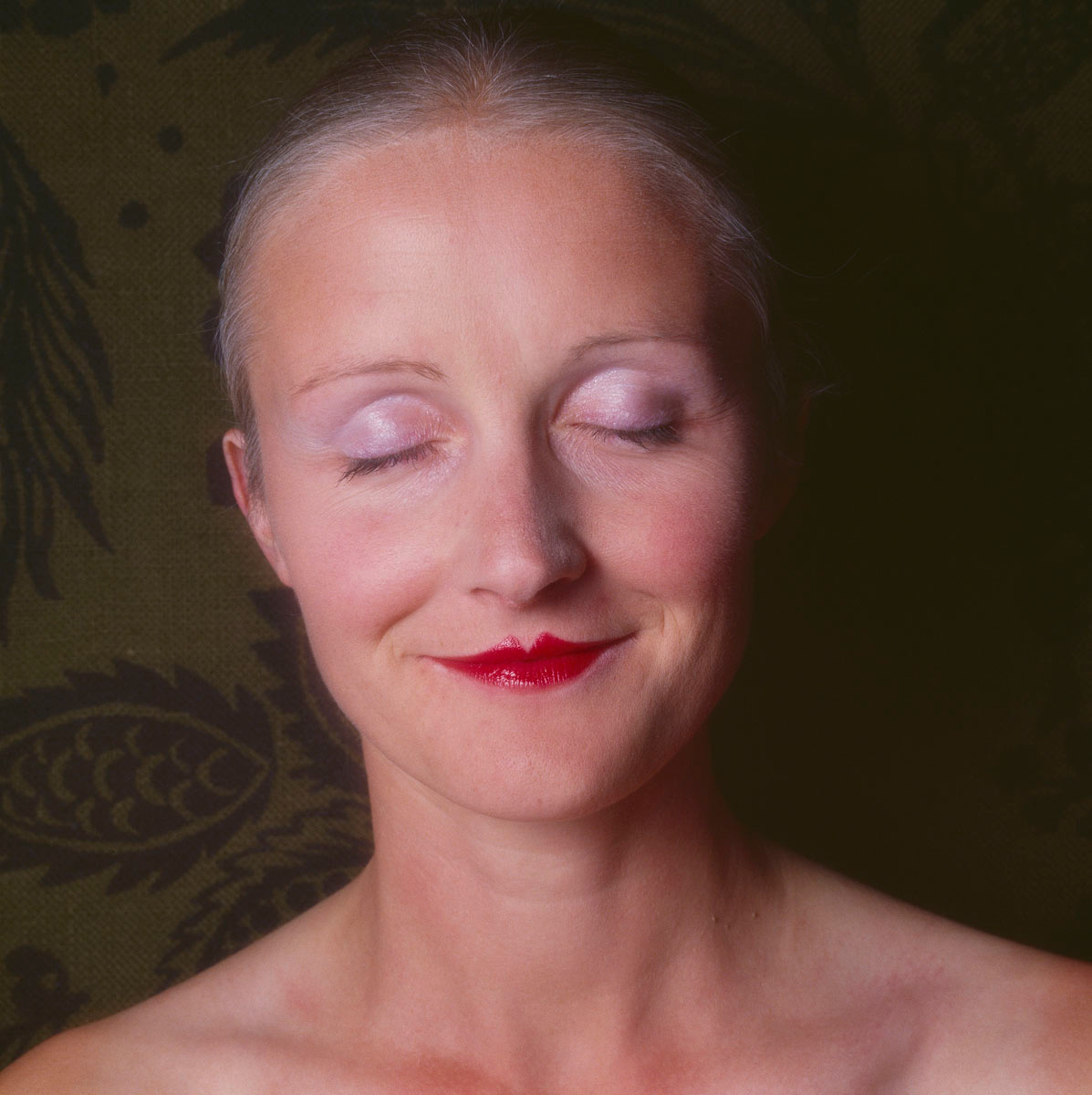 La photographie montre la tête d'une femme souriant les yeux fermés.