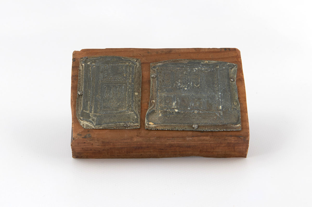 Vue de deux matrices de gravure en métal montées sur une planche en bois.