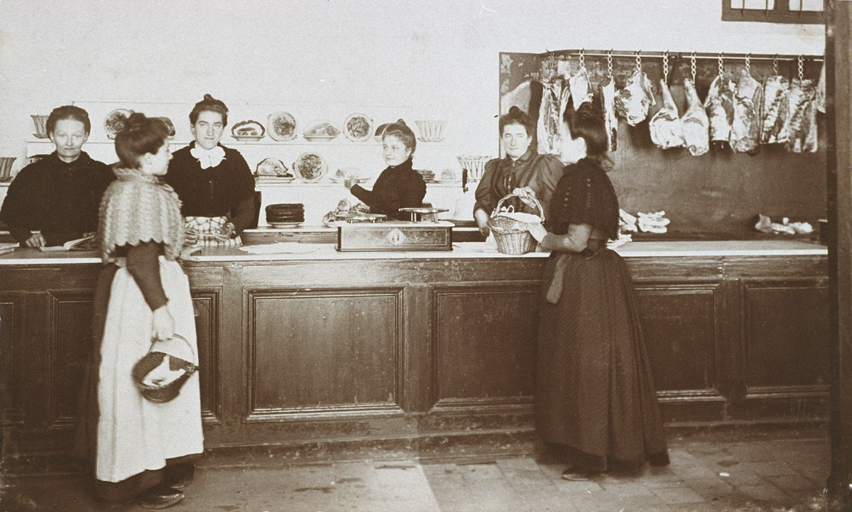 La photographie met en scène acheteuses et vendeuses de la boucherie.