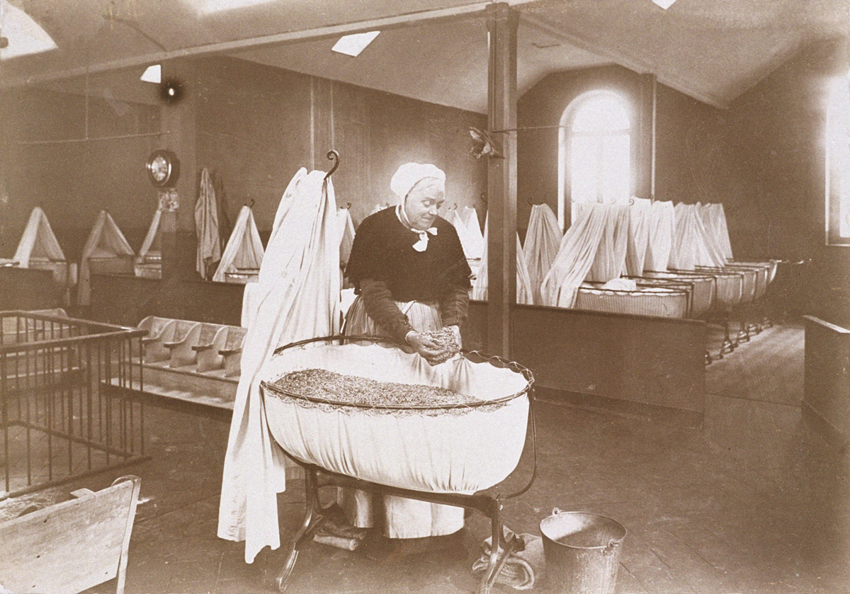 Madame Roger prépare le matelas d’un berceau de la nourricerie du Familistère.