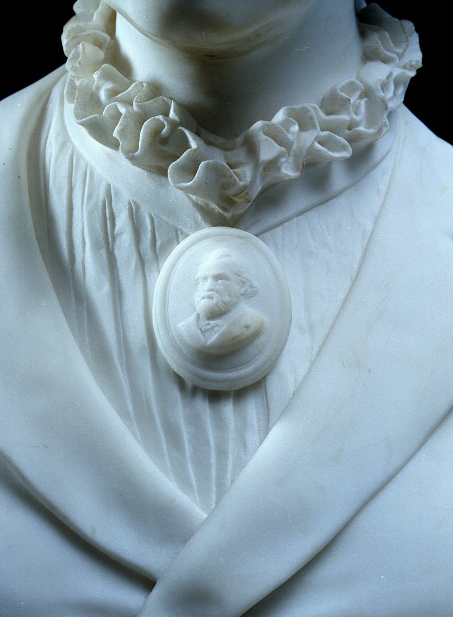 Sur le buste, Marie Moret porte au cou un camée à l'effigie de Godin.
