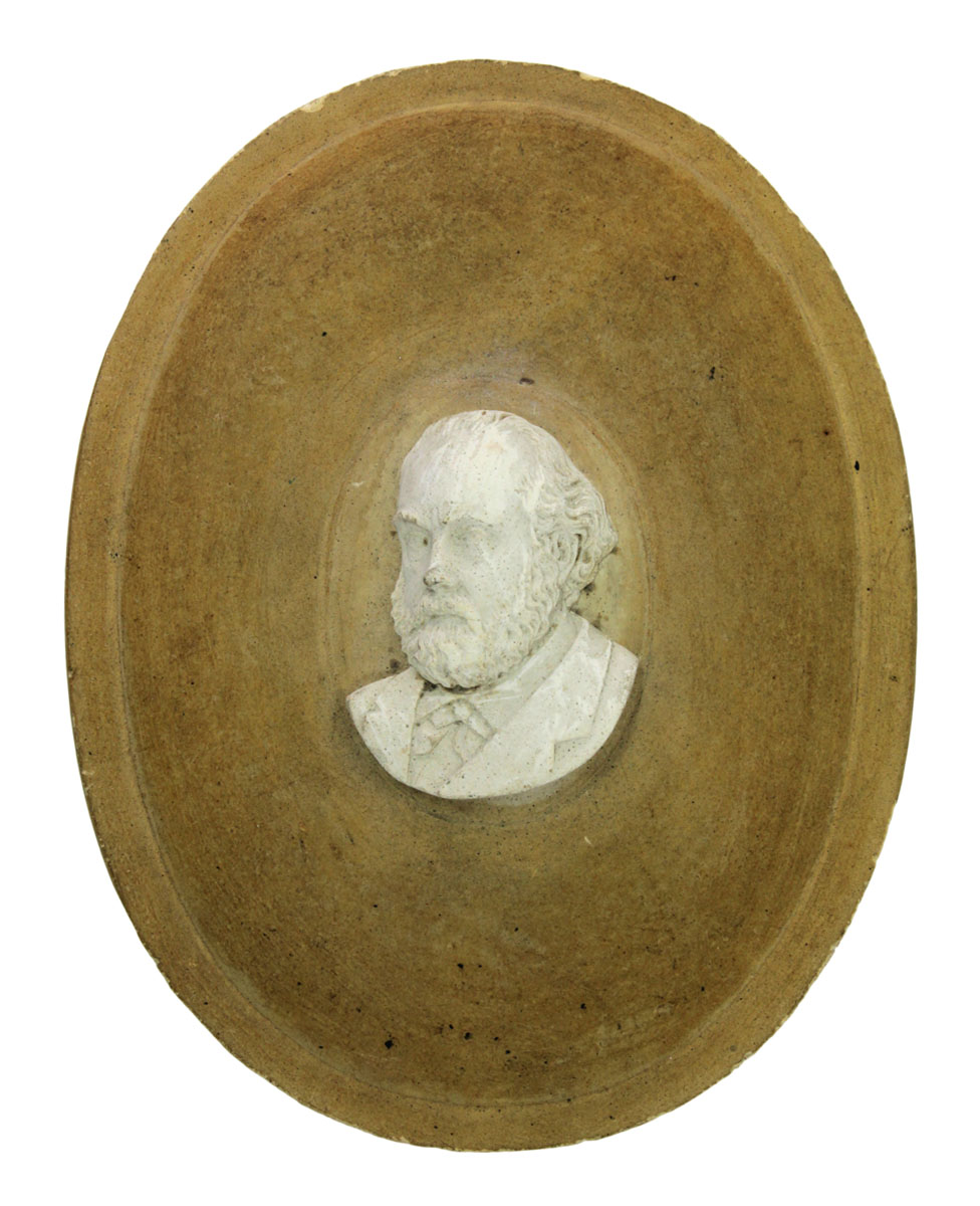 Le portrait en plâtre de Godin est fixé sur un médaillon en bois ovale.