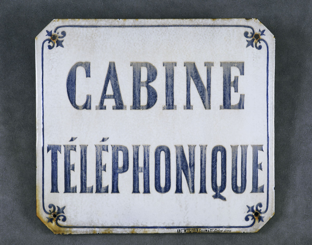 La plaque indicative présente un texte bleu sur fond ivoire.