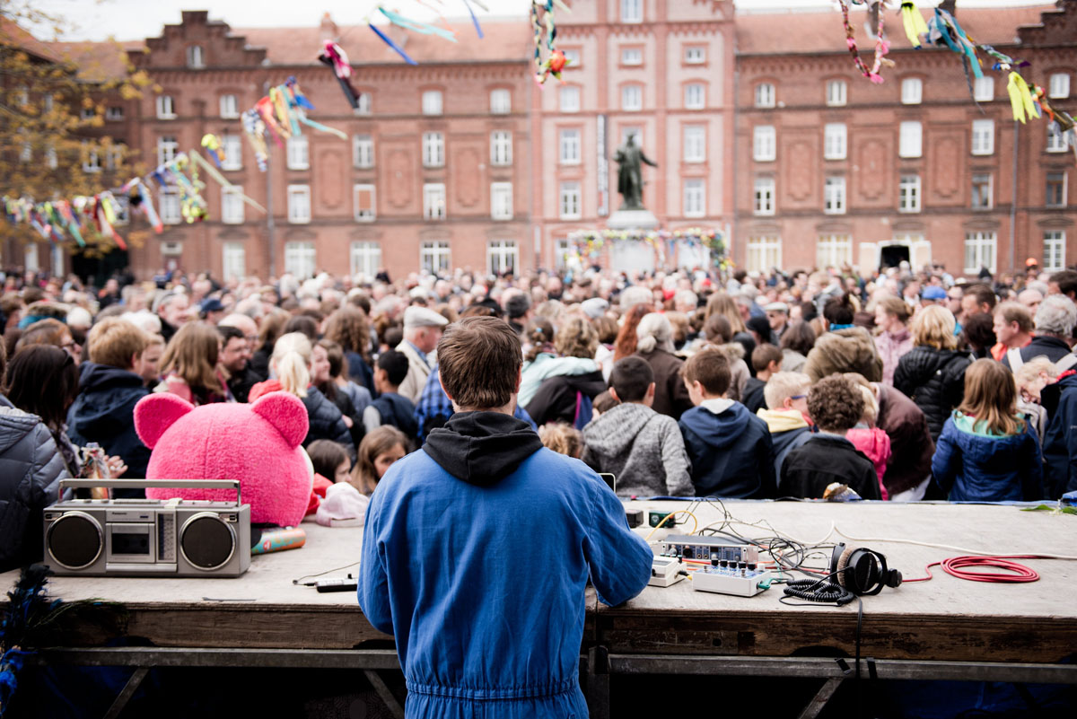 La photographie montre la foule sur la place du Familistère, devant le régisseur