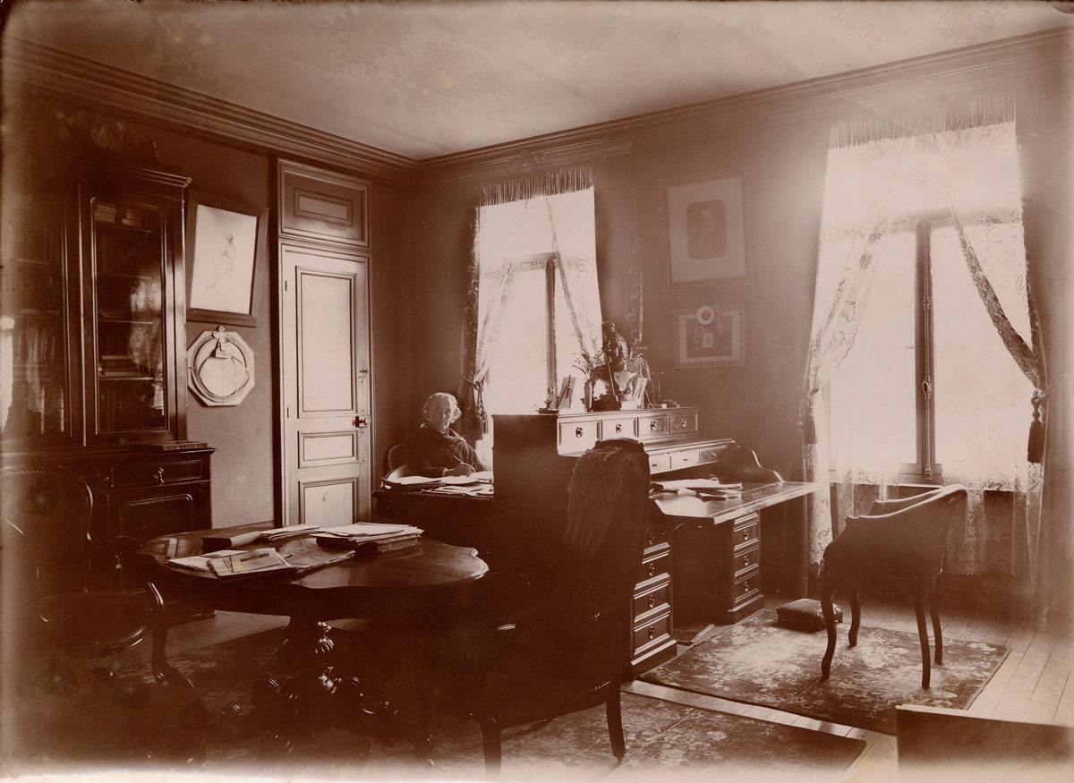 La photographie montre Marie Moret assise devant son bureau.