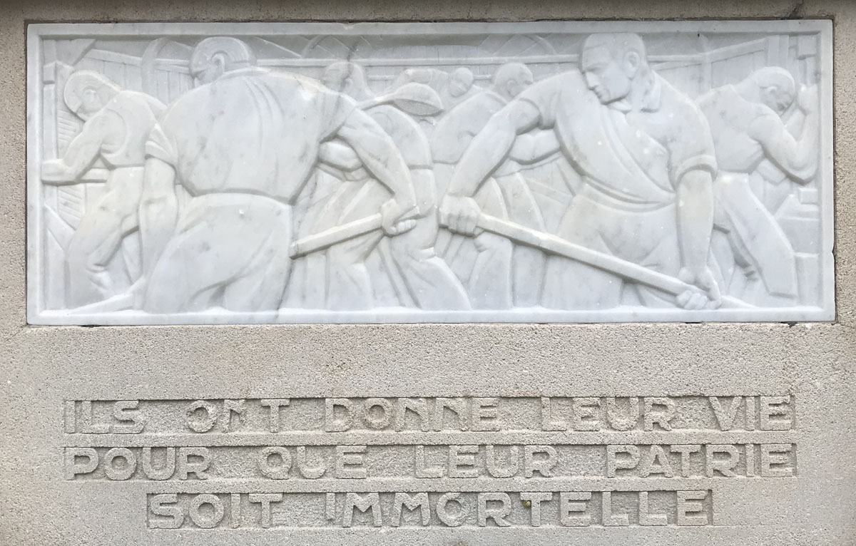 La photographie montre le relief situé à droite sur le monument aux morts du Fam