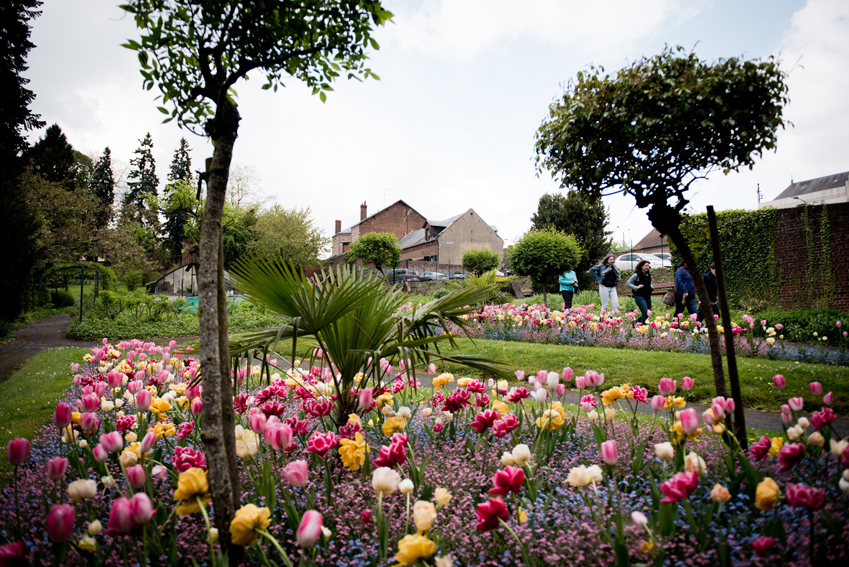 Un massif de felurs dans le jardin d'agrément et quelques visiteurs en arrière p