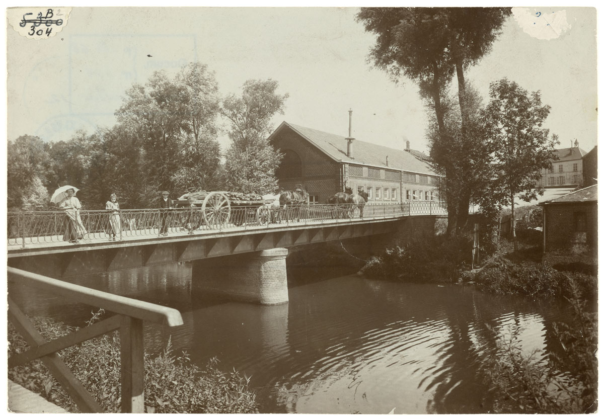 La photographie montre le pont sur l'Oise du Familistère.