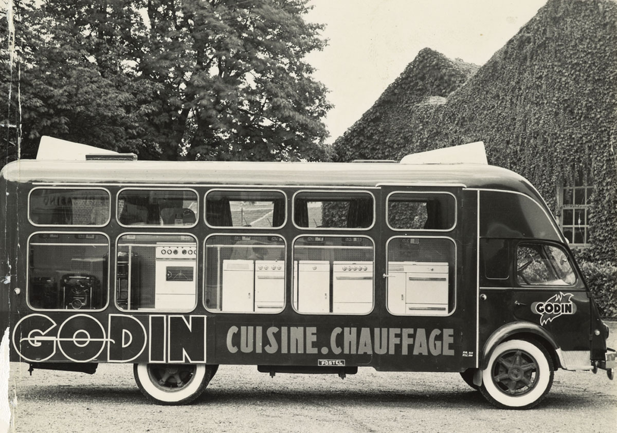 La photographie montre un camion publicitaire devant le théâtre du Familistère.