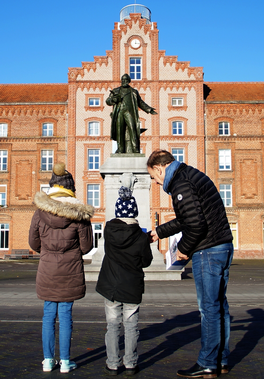 Un grand-père et ses deux petits-enfants sur la place du Familistère.