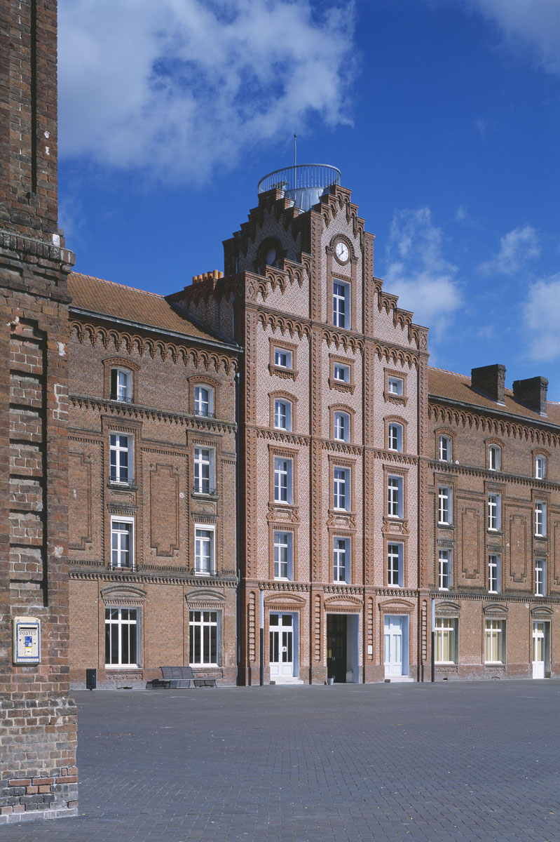 La photographie montre une boîte aux lettres au premier plan du Palais social.