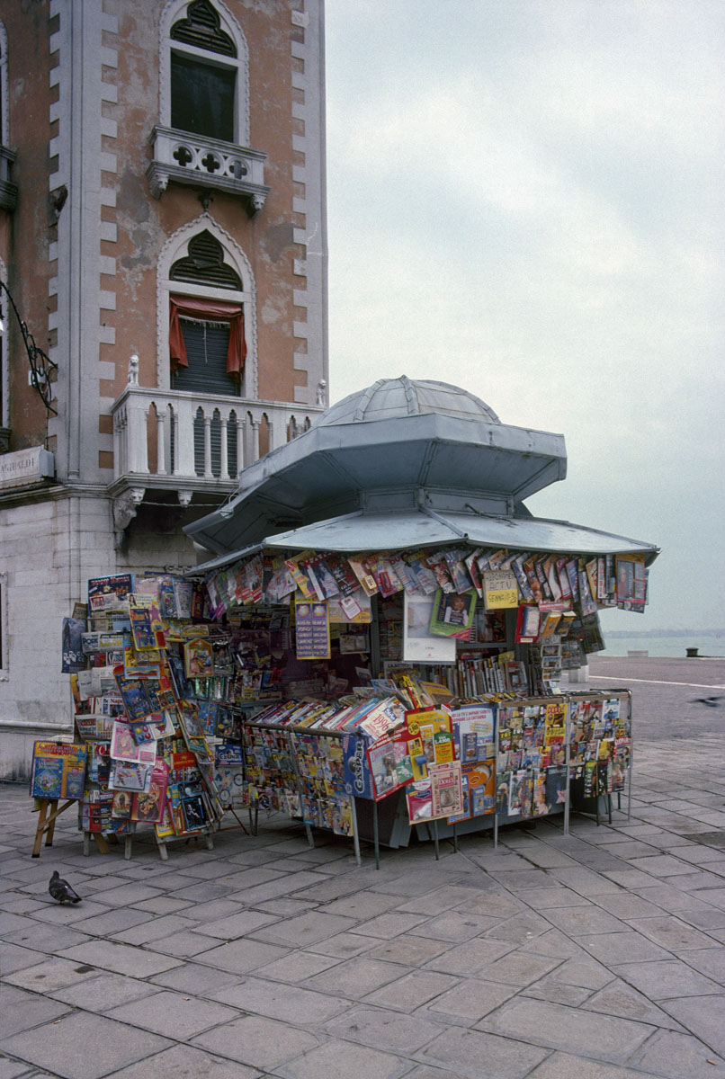 La photographie montre un kiosque à journaux surchargé.