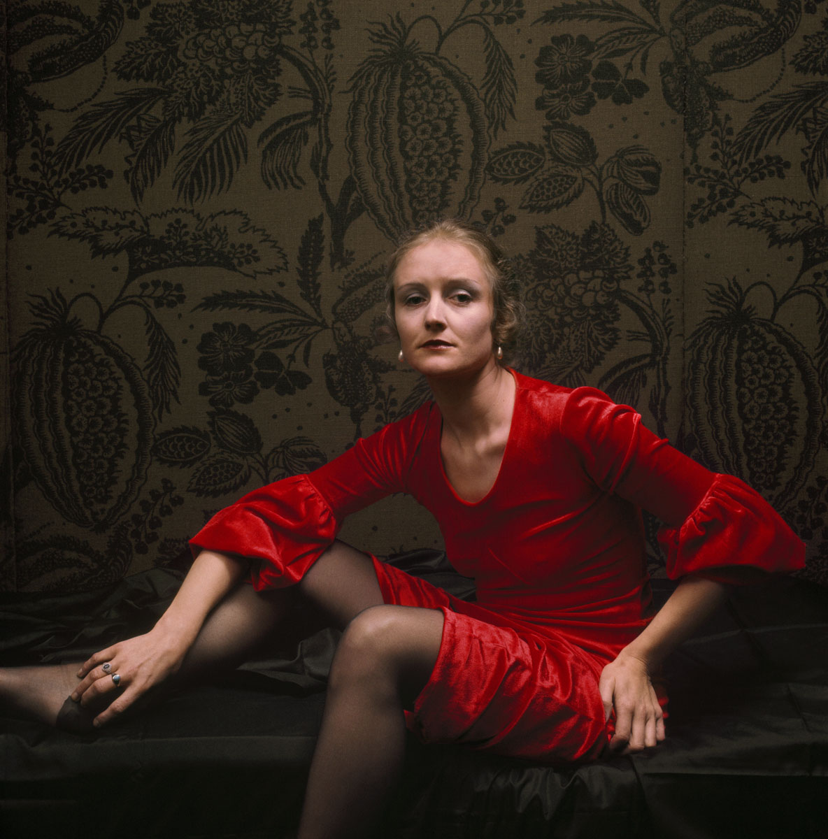 La photographie montre une femme habillée en rouge dans un intérieur.