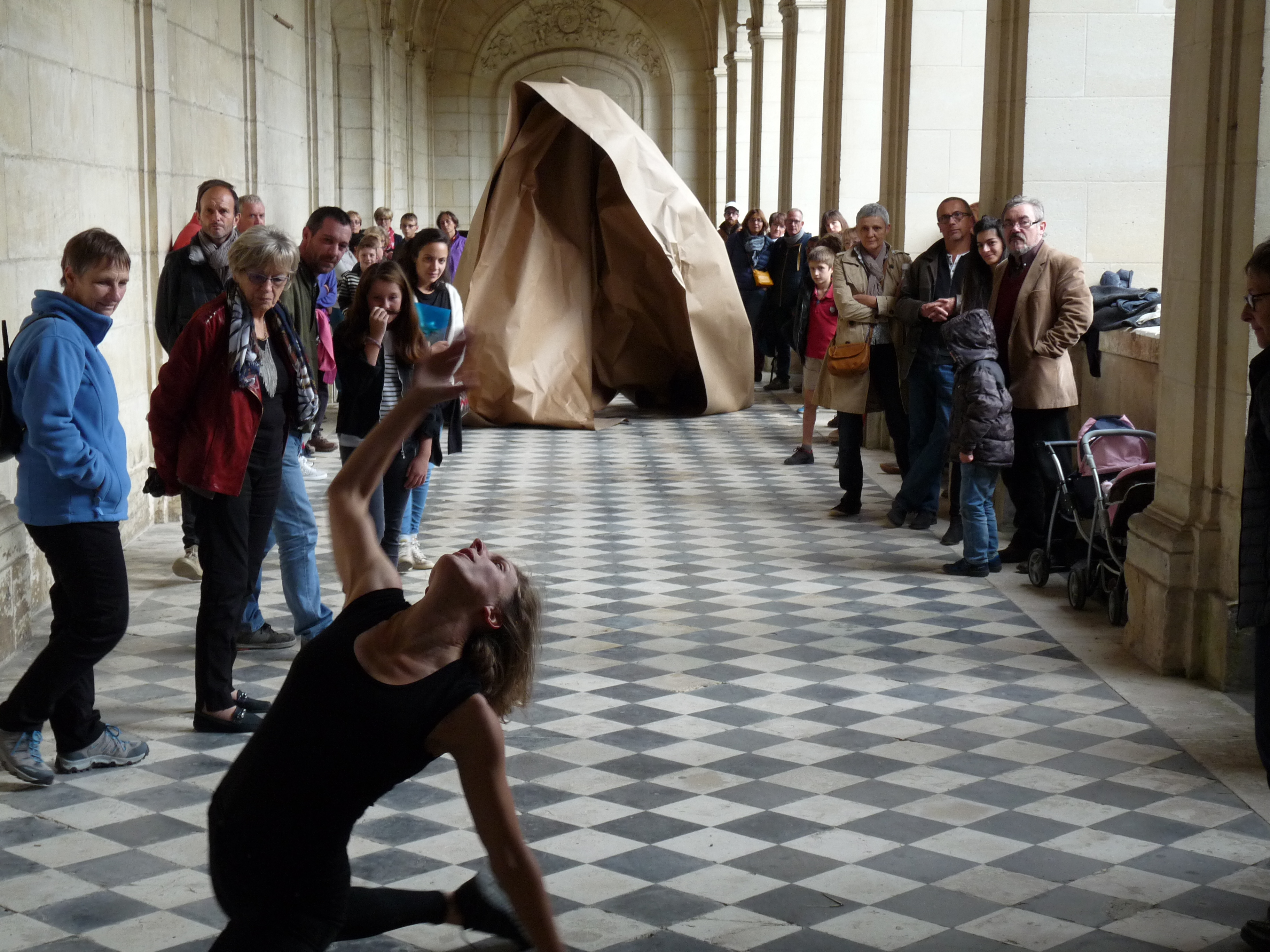 Une danseuse contemporaine au premier plan, une structure en papier craft en sec