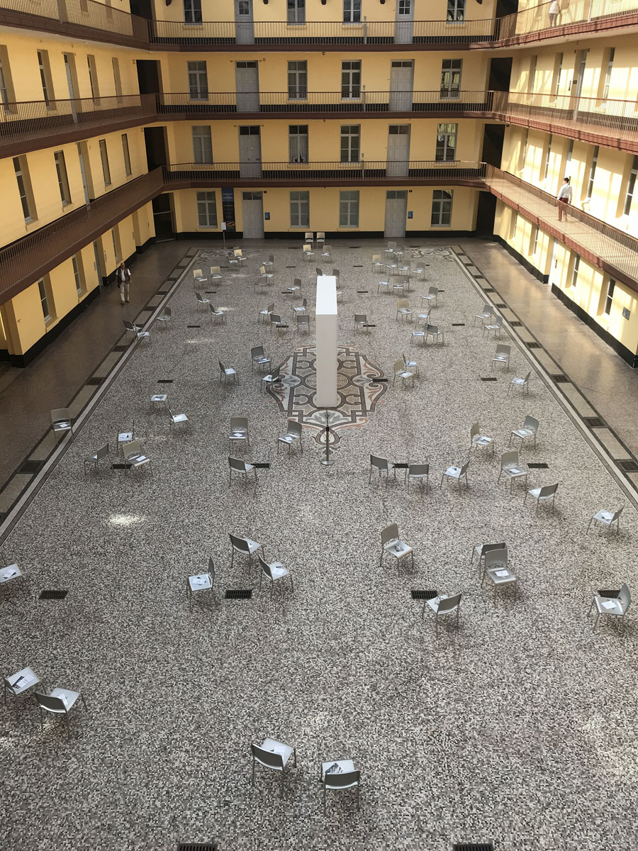 La photographie montre des chaises éparpillées dans la cour du pavillon central.